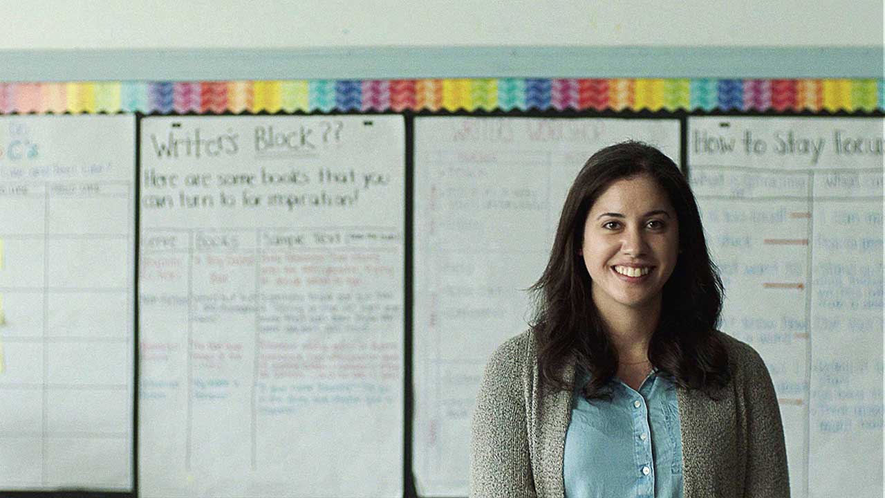 Teacher smiling in front of whiteboard